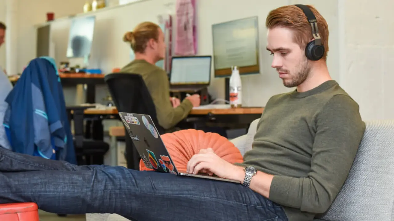 a man sitting on a couch using a laptop computer