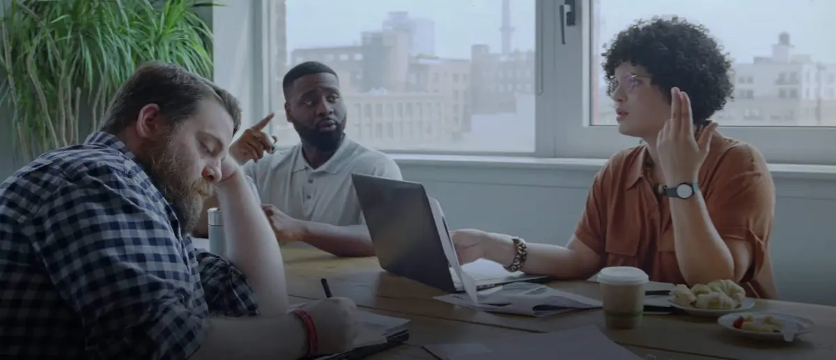 a group of people sitting around a table with a laptop